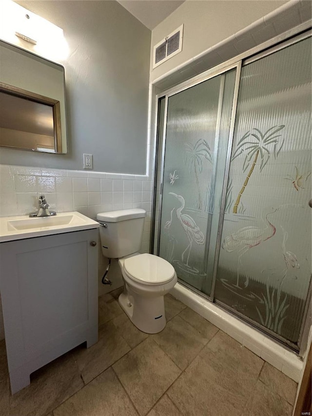 bathroom with tile walls, vanity, tile patterned floors, and toilet