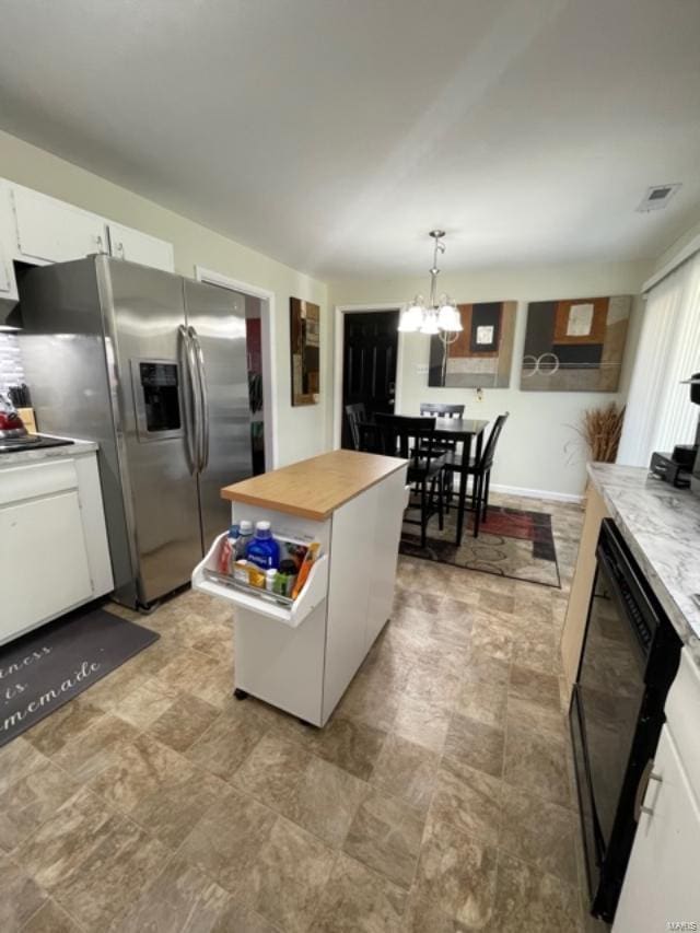 kitchen with hanging light fixtures, white cabinets, black dishwasher, a kitchen island, and an inviting chandelier