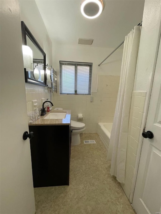 full bathroom featuring tile walls, vanity, toilet, and shower / tub combo