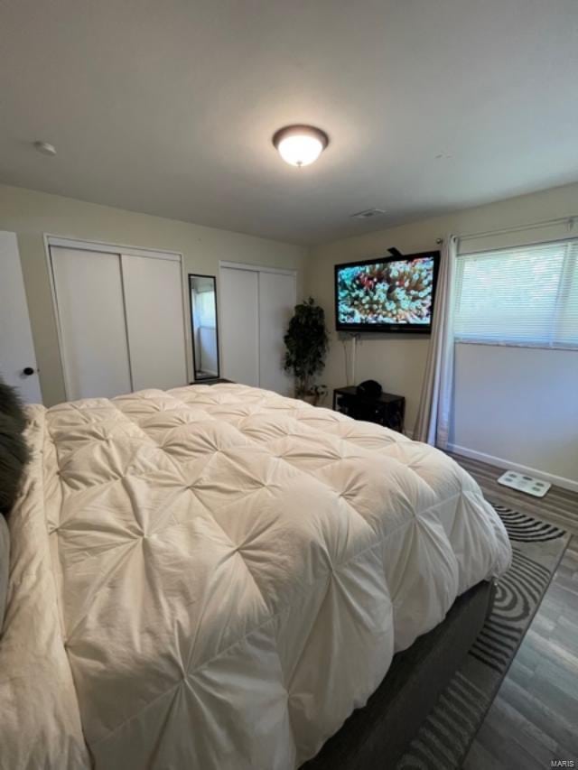 bedroom featuring two closets and hardwood / wood-style flooring