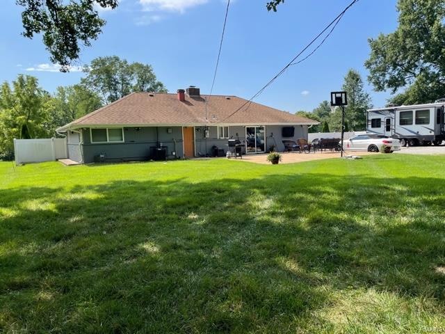 rear view of property with a lawn and a patio