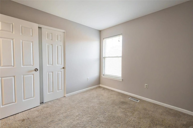 unfurnished bedroom with a closet and light colored carpet