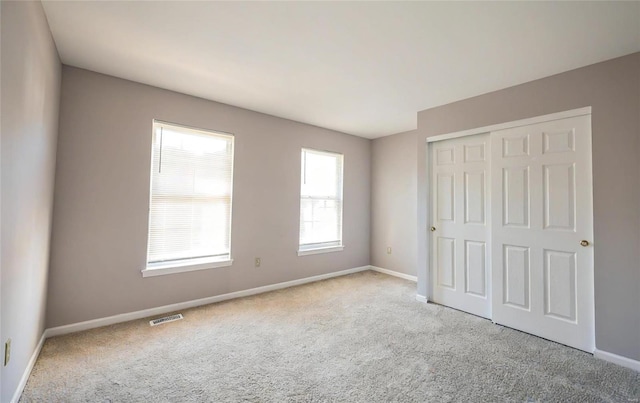 unfurnished bedroom featuring light carpet and a closet