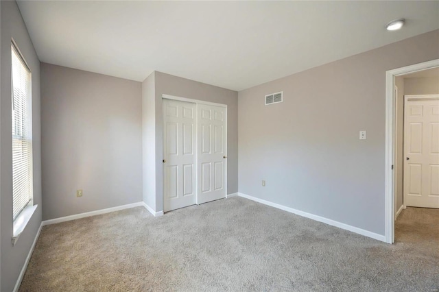 unfurnished bedroom with multiple windows, a closet, and light colored carpet