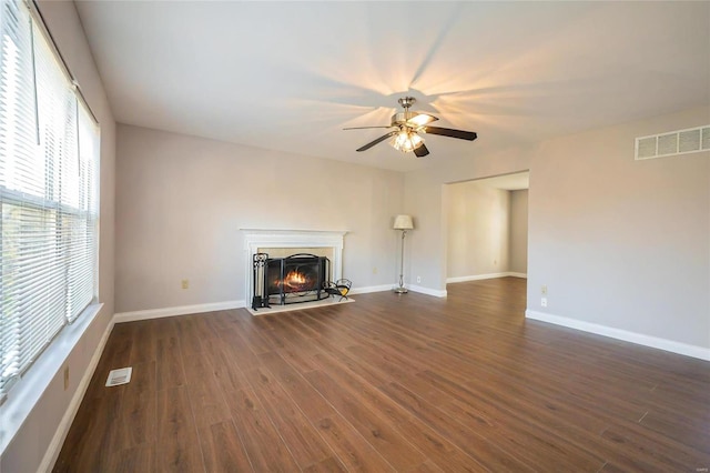 unfurnished living room featuring dark wood-type flooring and ceiling fan