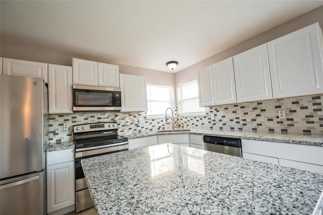 kitchen with appliances with stainless steel finishes, white cabinets, tasteful backsplash, and sink