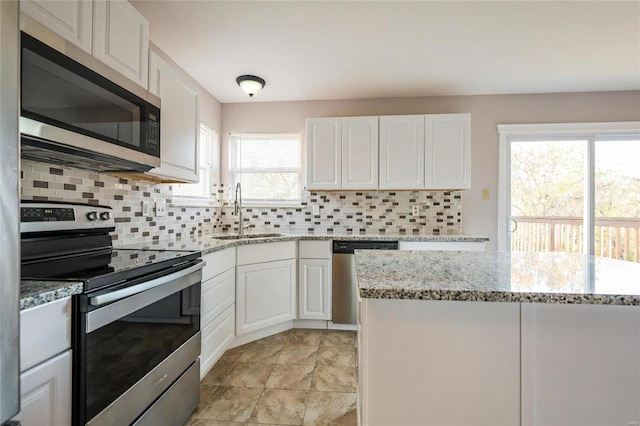 kitchen with appliances with stainless steel finishes, white cabinets, sink, and a wealth of natural light