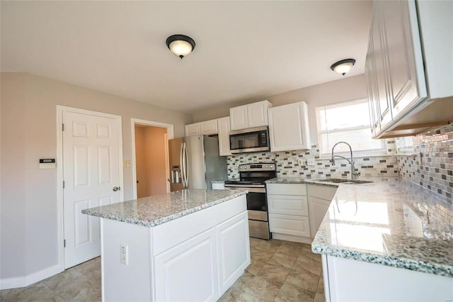 kitchen featuring tasteful backsplash, appliances with stainless steel finishes, sink, a kitchen island, and white cabinetry