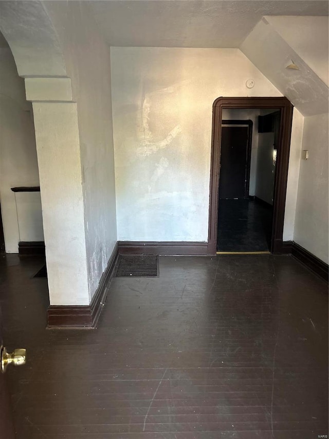 spare room with vaulted ceiling and dark hardwood / wood-style flooring