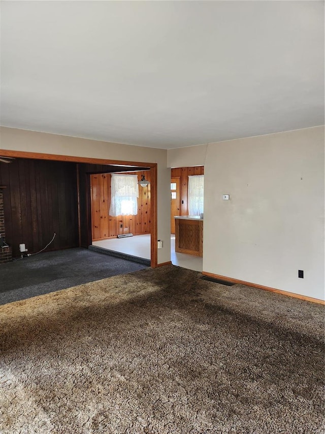 unfurnished room featuring wood walls and carpet