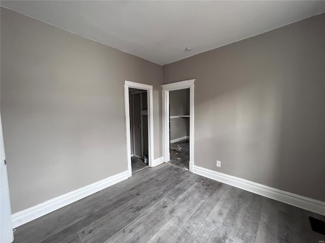 unfurnished bedroom with a walk in closet and wood-type flooring