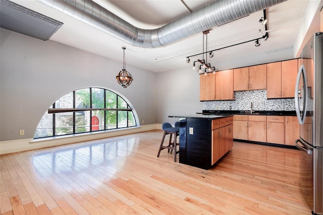 kitchen with decorative light fixtures, dark countertops, a kitchen island, and freestanding refrigerator