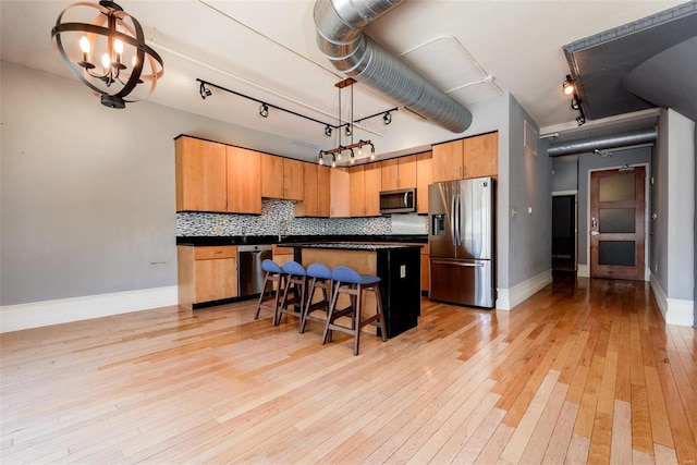 kitchen featuring dark countertops, a breakfast bar area, hanging light fixtures, stainless steel appliances, and a notable chandelier