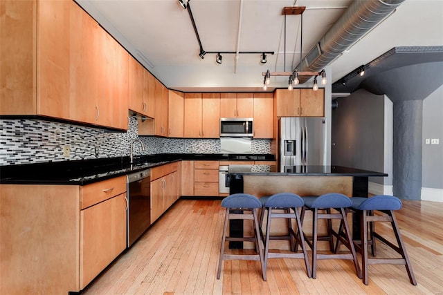 kitchen with a center island, dark countertops, light wood-style floors, and stainless steel appliances