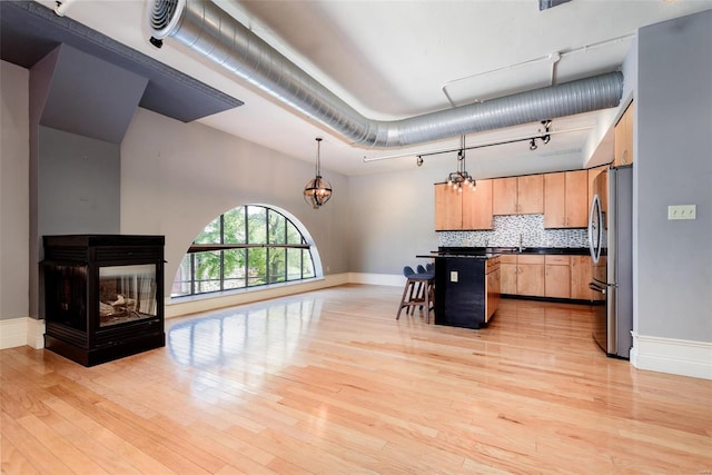 kitchen featuring dark countertops, freestanding refrigerator, open floor plan, hanging light fixtures, and a kitchen breakfast bar