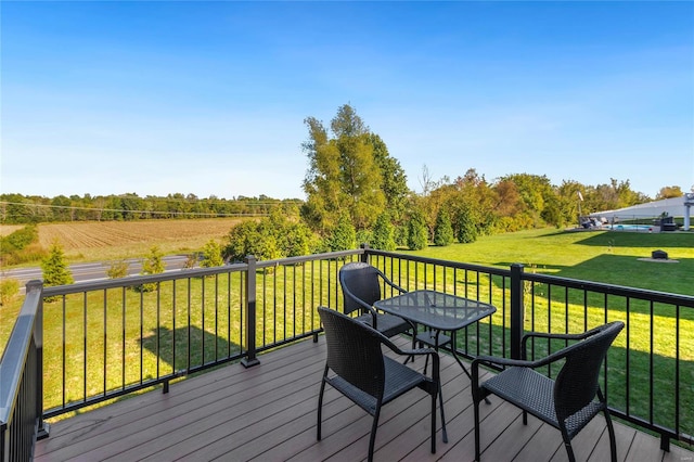 wooden deck featuring a rural view and a yard