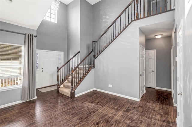 foyer with a towering ceiling and dark hardwood / wood-style flooring