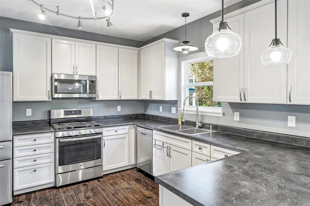 kitchen featuring appliances with stainless steel finishes, sink, dark hardwood / wood-style flooring, white cabinetry, and decorative light fixtures