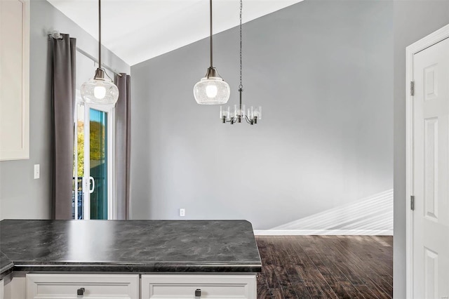 kitchen featuring lofted ceiling, white cabinets, hanging light fixtures, and hardwood / wood-style floors