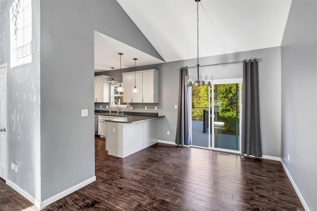 kitchen with kitchen peninsula, white cabinets, hanging light fixtures, dark hardwood / wood-style floors, and sink