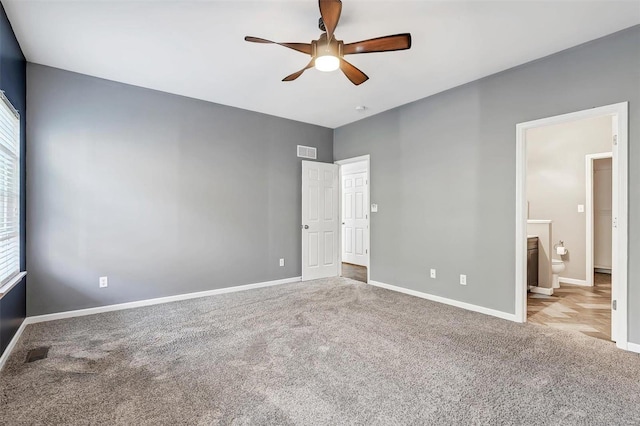 unfurnished bedroom featuring ensuite bathroom, light colored carpet, and ceiling fan