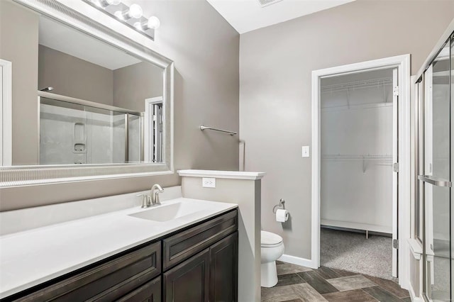 bathroom featuring vanity, a shower with shower door, and toilet