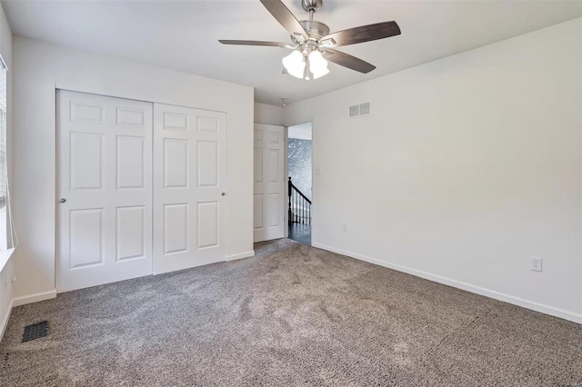 unfurnished bedroom featuring a closet, multiple windows, carpet, and ceiling fan