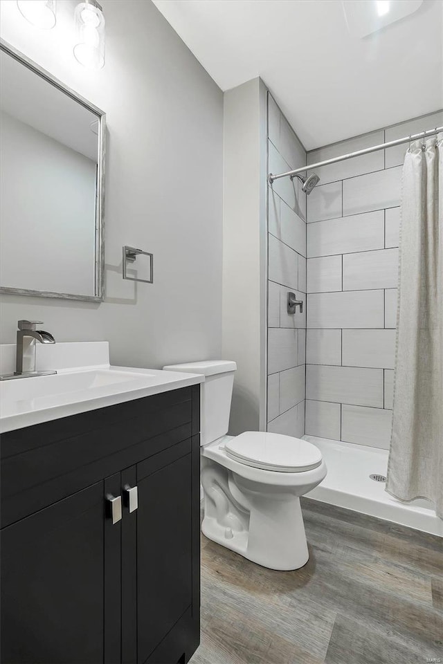 bathroom with toilet, a shower with curtain, vanity, and hardwood / wood-style flooring