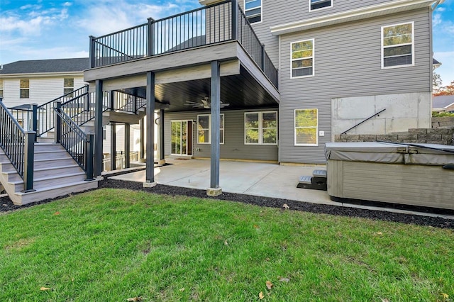 back of house with a patio, a hot tub, a lawn, and a wooden deck