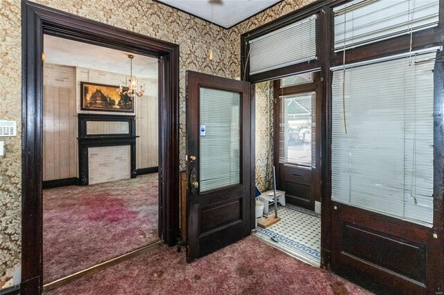 carpeted foyer entrance with a notable chandelier