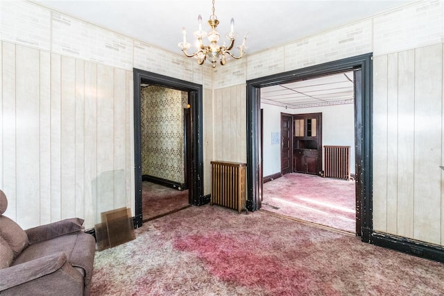 interior space with radiator, wood walls, carpet floors, and a chandelier