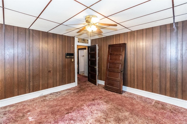 interior space with wood walls, a paneled ceiling, and ceiling fan