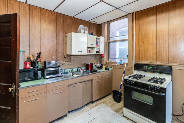 kitchen with a paneled ceiling, white gas range, and wooden walls