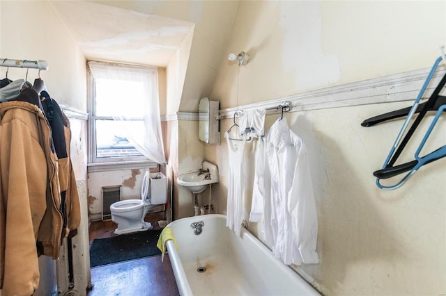 bathroom featuring sink, concrete flooring, toilet, lofted ceiling, and a bathtub