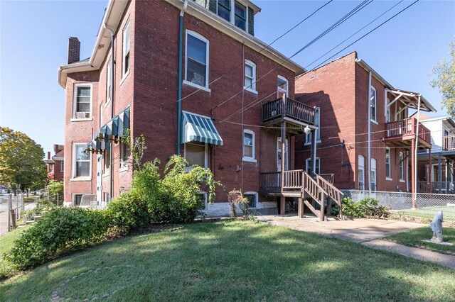 back of property with a yard and a balcony