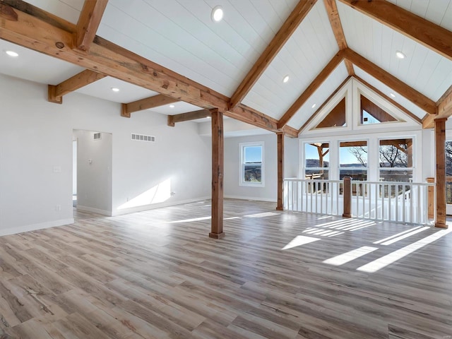 unfurnished living room with beam ceiling, wood-type flooring, and high vaulted ceiling