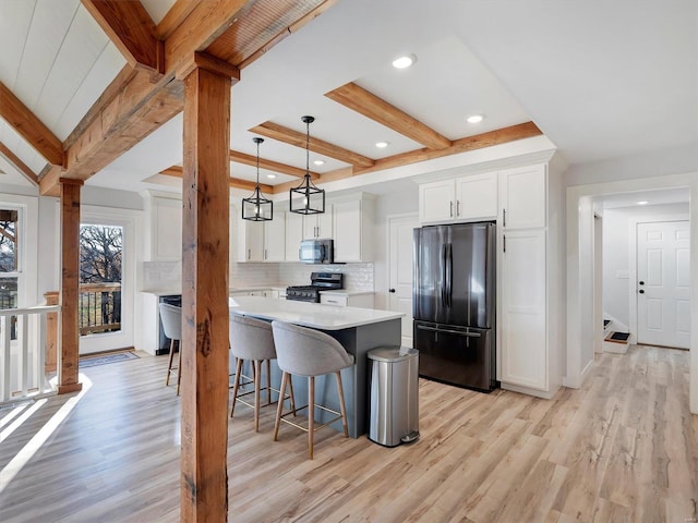 kitchen with white cabinets, stainless steel appliances, light hardwood / wood-style flooring, and hanging light fixtures