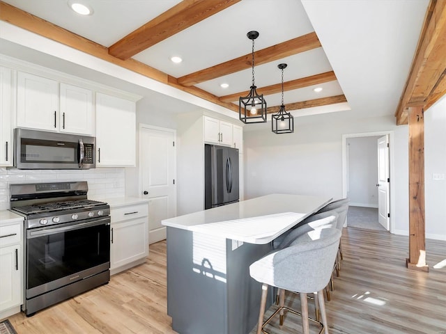 kitchen with white cabinets, tasteful backsplash, decorative light fixtures, light hardwood / wood-style floors, and stainless steel appliances