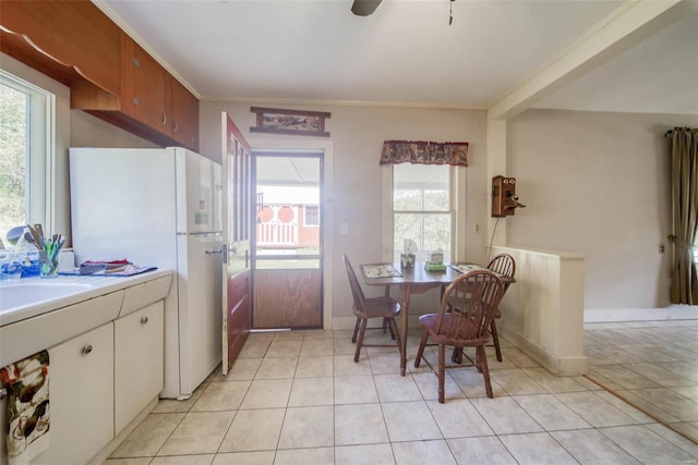 kitchen featuring ornamental molding, a wealth of natural light, white refrigerator, and light tile patterned flooring