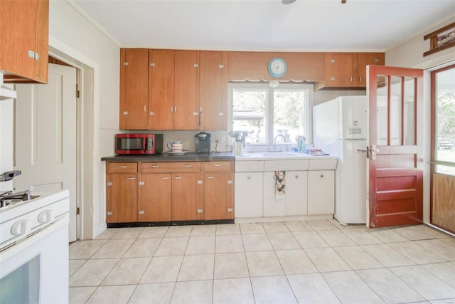 kitchen featuring light tile patterned floors, crown molding, sink, and white appliances