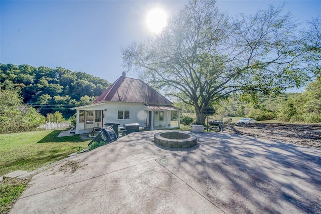 back of property with a lawn, a patio, and an outdoor fire pit