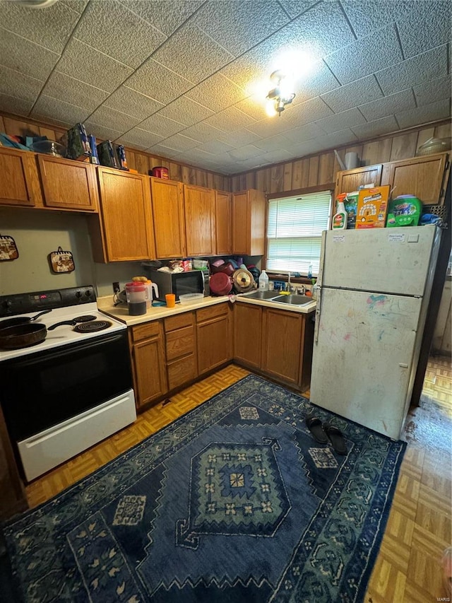 kitchen with white appliances, light parquet floors, and sink