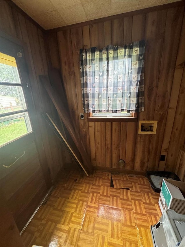 doorway featuring wooden walls, a drop ceiling, and light parquet floors