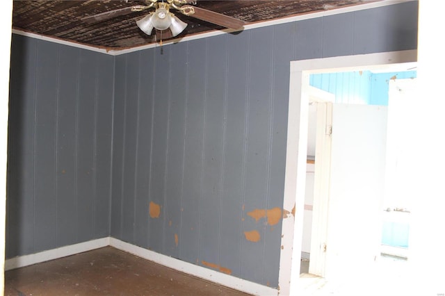 unfurnished room featuring wooden walls and ceiling fan