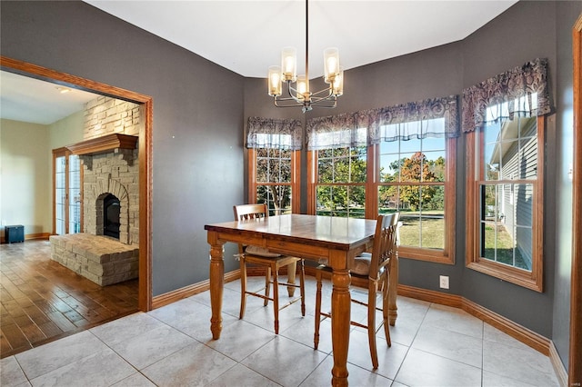 tiled dining space featuring a stone fireplace and an inviting chandelier