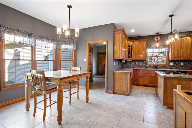 kitchen with tasteful backsplash, light stone countertops, and decorative light fixtures