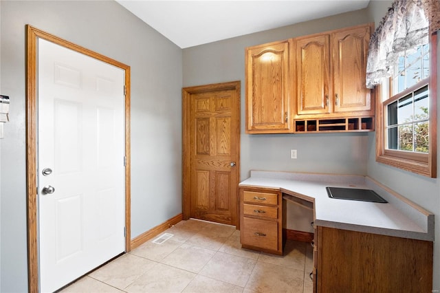 unfurnished office featuring light tile patterned floors and built in desk