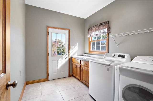 laundry room with cabinets, washing machine and dryer, a healthy amount of sunlight, and light tile patterned flooring