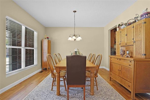 dining room featuring light wood-type flooring, a chandelier, and a healthy amount of sunlight