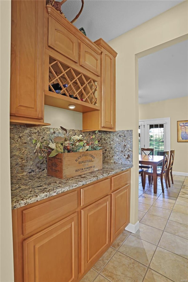 kitchen with decorative backsplash, light stone countertops, and light tile patterned floors